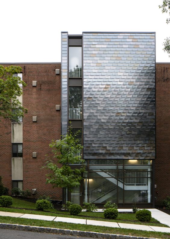 Intricate Stair Tower AdditionThe new exit stair was carefully designed to transform a dated brick facade into a point of interest utilizing glass and metal panels that mimic the wood siding found on adjacent residential structures.