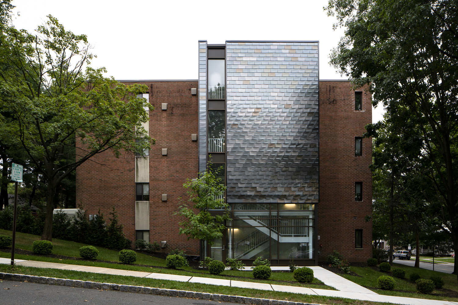 Intricate Stair Tower Addition The new exit stair was carefully designed to transform a dated brick facade into a point of interest utilizing glass and metal panels that mimic the wood siding found on adjacent residential structures.